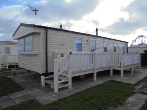 a mobile home with a porch and a fence at Kingfisher Mistral 8 Berth, Central Heated, Close to site exit FREE WIFI in Ingoldmells