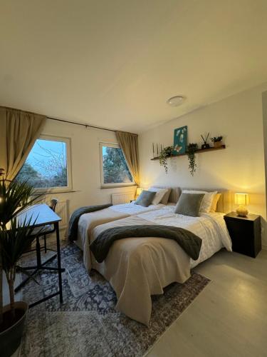 a bedroom with two beds and a table and two windows at Central Peaceful Villa, Malmö in Malmö