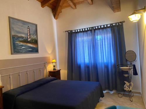 sypialnia z niebieskim łóżkiem i oknem z latarnią morską w obiekcie Oasi Turchese Sardegna w mieście Trinità dʼAgultu