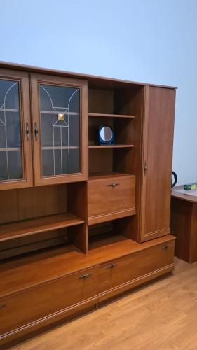 un centro di intrattenimento in legno con porte in vetro e cassetti di Студия в центре a Astana