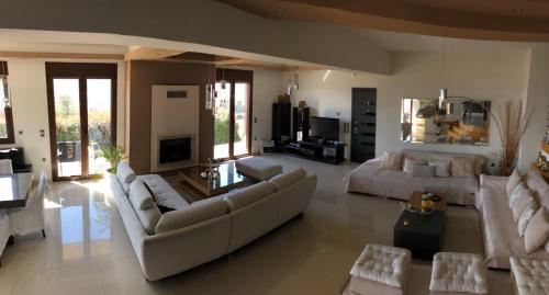 una gran sala de estar con sofás y TV. en Villa Under Meteora, en Kalambaka