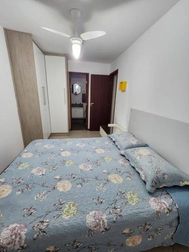 a bedroom with a bed with a blue blanket with flowers at Prédio Frente Mar Praia da Costa 08 in Vila Velha