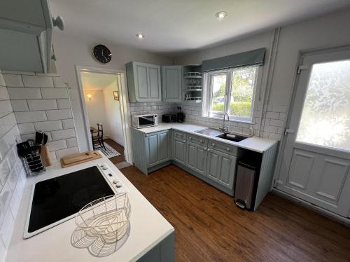 een keuken met grijze kasten en een wit aanrecht bij The Cottage, Shalfleet House in Shalfleet