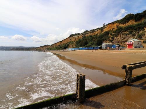 a beach with houses and the ocean and a hill at The Beach Retreat - Pet Friendly in Sandown