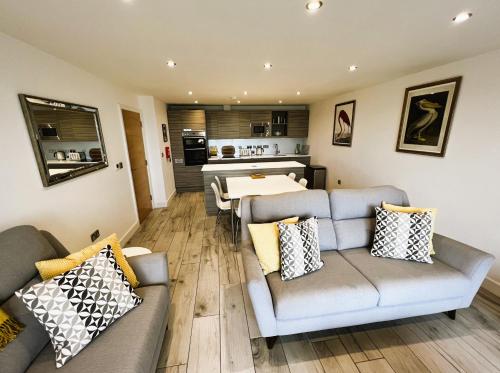 a living room with two couches and a kitchen at The Beach Retreat in Sandown