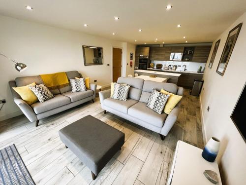 a living room with two couches and a kitchen at The Beach Retreat in Sandown