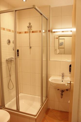 uma casa de banho com um chuveiro e um lavatório. em Isar City Hotel em Munique