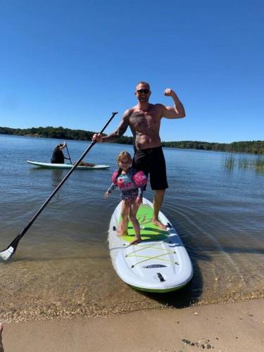 a man and a child on a paddle board in the water at Escape to Nature and Lake views Studio Style Rooms in Clitherall