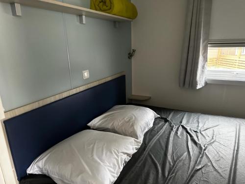 ein Bett mit zwei Kissen auf einem Zimmer in der Unterkunft Mobilhome clim La Falaise 4 étoiles in Narbonne