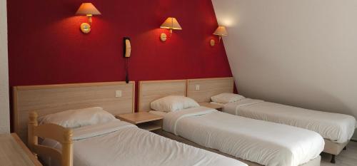 three beds in a room with red walls at Hotel C&Ouml;RONA Lourdes in Lourdes