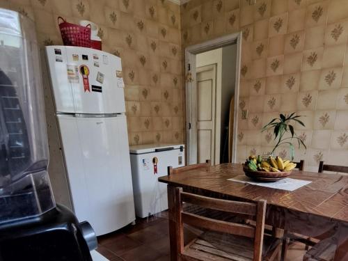 a kitchen with a table and a white refrigerator at Casa Pé na Areia Cantão do Bora Bora - Manaaki Surf Hostel in São Sebastião