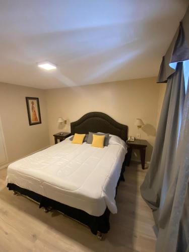a bedroom with a large white bed with yellow pillows at Hotel Metropol in San Miguel de Tucumán