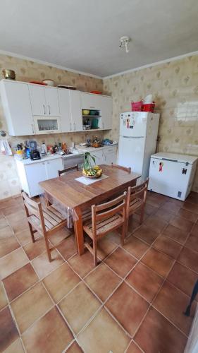 a kitchen with a wooden table and chairs and a kitchen with white appliances at Casa Pé na Areia Cantão do Bora Bora - Manaaki Surf Hostel in São Sebastião