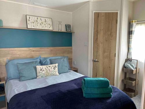 1 dormitorio con cama azul y cabecero azul en Hoburne Devon Bay - Hot Tub 2 Bed Paignton, en Paignton