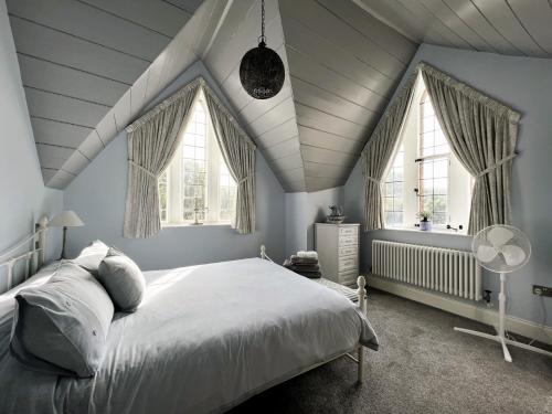 um quarto com uma cama branca e 2 janelas em The Old Abbey Farmhouse - Pet Friendly em Ryde
