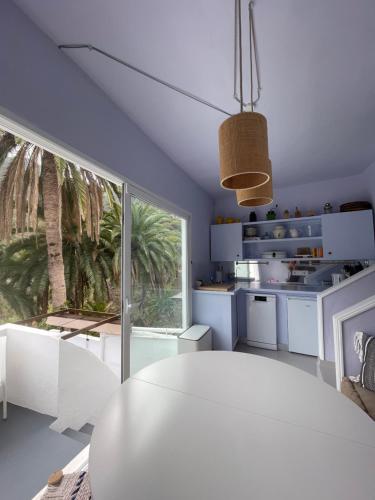 a kitchen with a white table and a large window at TheharmonyhouseTaganana in Taganana