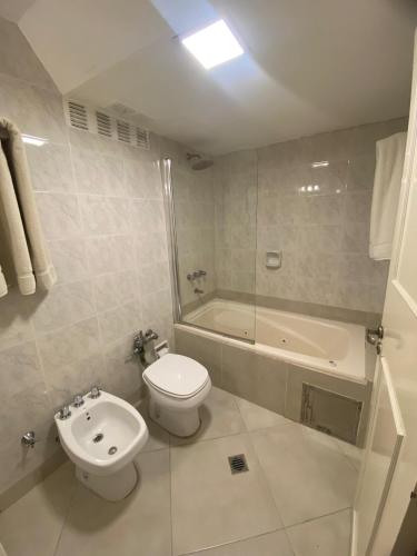 a bathroom with a toilet and a sink and a bath tub at Hotel Metropol in San Miguel de Tucumán