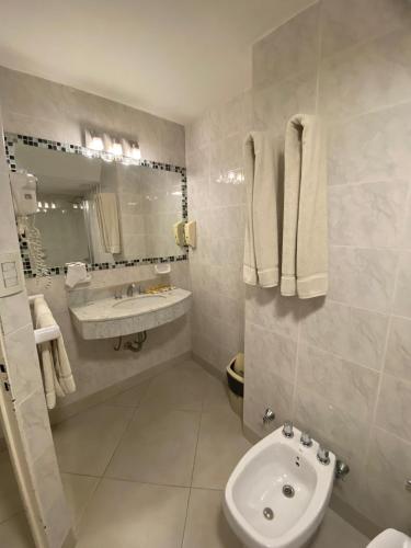 a white bathroom with a sink and a toilet at Hotel Metropol in San Miguel de Tucumán