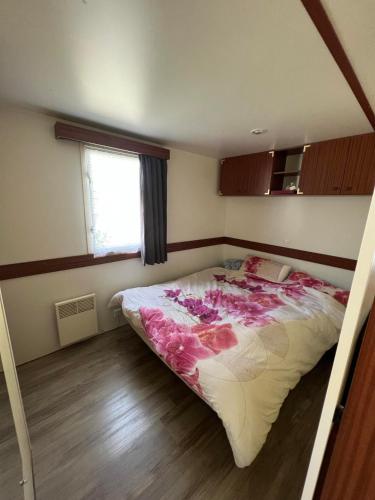 - une chambre avec un grand lit fleuri dans l'établissement Mobil-home au camping La Lande à Mimizan n°507, à Mimizan