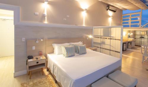 a bedroom with a large white bed and a kitchen at Lizon Curitiba Hotel in Curitiba