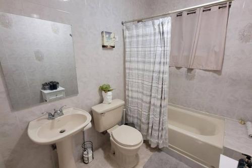 a bathroom with a toilet and a sink and a tub at Coamo Beautiful house, AC, 10min Coamo hot springs in Coamo