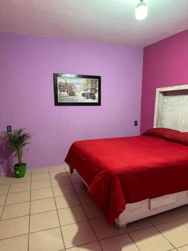 Schlafzimmer mit einem roten Bett und lila Wänden in der Unterkunft Habitación privada en casa compartida. in Tepic
