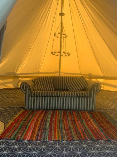 a couch in a tent with a rug at Bell Tent in Horspath