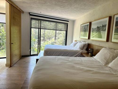 une chambre d'hôtel avec deux lits et une grande fenêtre dans l'établissement Suite boutique Oyamel en Avándaro, Valle de Bravo, à Valle de Bravo