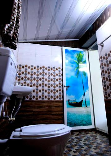 a bathroom with a toilet and a picture of a beach at The wayside cottage Munnar in Munnar