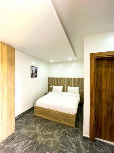 um quarto com uma cama branca e uma porta de madeira em BiggysPlace em Ijebu Ode