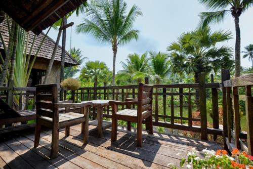 a table and chairs on a deck with palm trees at The Spa Koh Chang Resort in Ko Chang