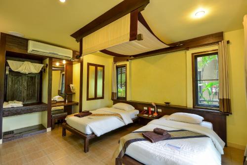 two beds in a room with yellow walls at The Spa Koh Chang Resort in Ko Chang