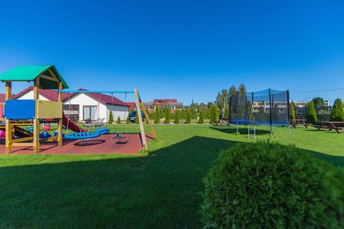 einen Park mit Spielplatz mit Schaukel in der Unterkunft Bursztyn II Domki Apartamenty Pokoje w Sarbinowie blisko morza in Sarbinowo