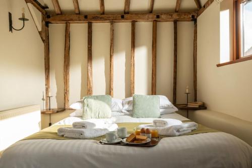 Una cama con toallas y una bandeja de comida. en Byre, en Herstmonceux