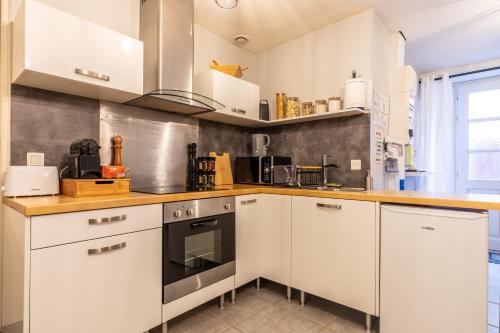 a kitchen with white cabinets and a stove at Nid douillet - Elégant studio en plein centre de Riom in Riom