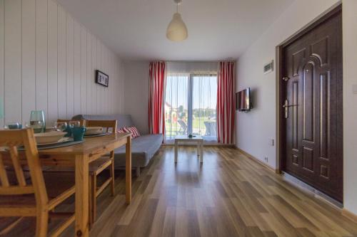 ein Wohnzimmer mit einem Tisch und einem Esszimmer in der Unterkunft Bursztyn II Domki Apartamenty Pokoje w Sarbinowie blisko morza in Sarbinowo