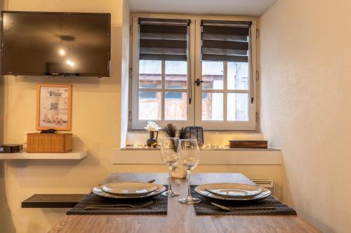 une table avec deux verres et assiettes et une fenêtre dans l'établissement Nid douillet - Elégant studio en plein centre de Riom, à Riom