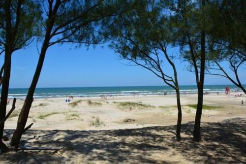um grupo de árvores numa praia perto do oceano em Casa de Praia Aconchegante e Próxima da Praia em Arroio do Sal