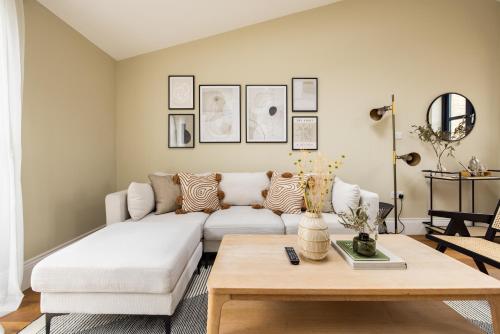 ein Wohnzimmer mit einem weißen Sofa und einem Tisch in der Unterkunft The Tooting Hideout - Dazzling 3BDR Flat with Balcony in London