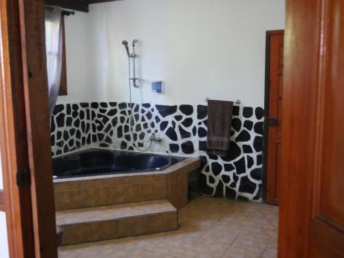a bathroom with a tub and a black and white patterned wall at Hotel Mandacarú Puerto Viejo in Puerto Viejo