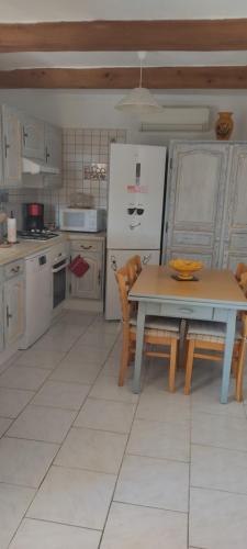 eine Küche mit einem Tisch und einem Kühlschrank in der Unterkunft Les garrigues in Pernes-les-Fontaines
