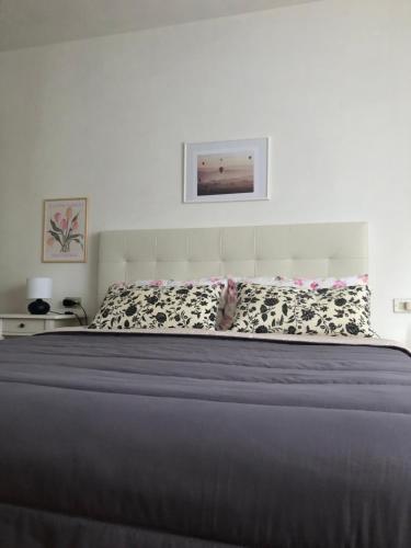 1 dormitorio con 1 cama grande con almohadas blancas y negras en ScacciaPensieri vicino al Policlinico e al Centro città, en Siena