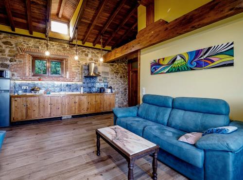 a living room with a blue couch and a kitchen at Precioso apartamento en plena naturaleza in La Cavada