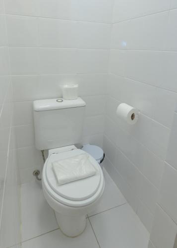 a white bathroom with a toilet with a roll of toilet paper at Lizon Curitiba Hotel in Curitiba