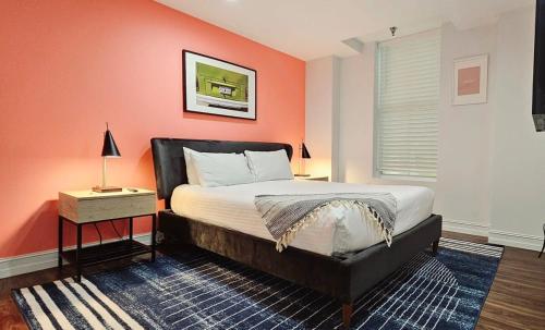 a bedroom with a bed with an orange wall at The Lofts on Clematis 405 Downtown West Palm Beach in West Palm Beach