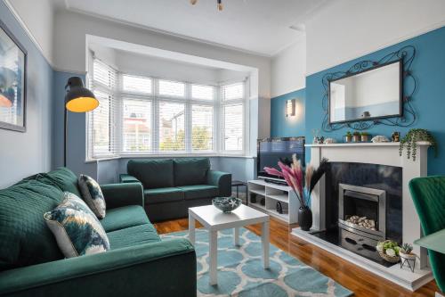 sala de estar con sofá verde y chimenea en New - Stylish 4 bedroom House, Business & Leisure. Discount on long stays. By Jesswood Properties., en Southend-on-Sea