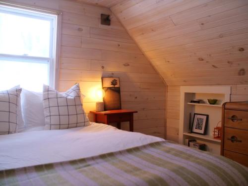 1 dormitorio con 1 cama en una habitación con paredes de madera en Chalet “Lendemain de ville” avec accès au lac, en Saint Adolphe D'Howard