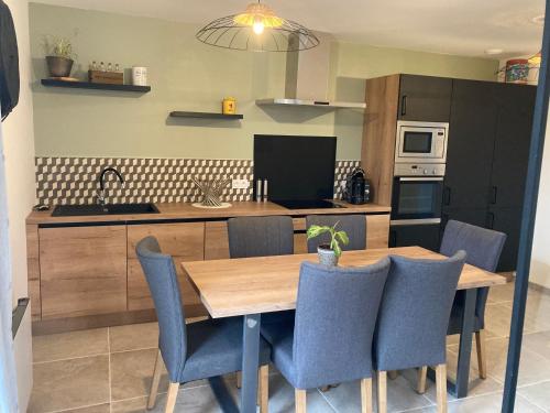 une cuisine avec une table en bois et des chaises bleues dans l'établissement Gîtes des Guettes, à Saint-Suliac