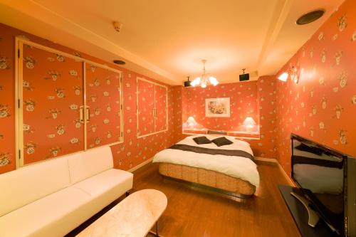 a bedroom with red walls with a bed and a couch at Hotel Public Jam in Osaka