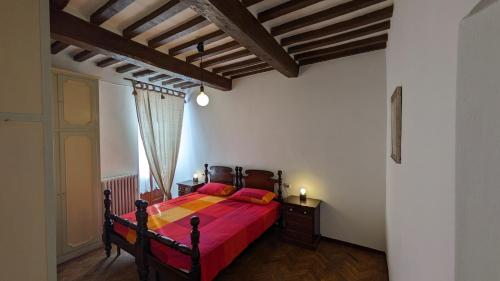 een slaapkamer met een bed met een rode sprei bij Borgo Antico in Gubbio